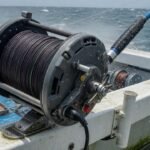 Electric reel mounted on a boat rail over open ocean — deep drop fishing