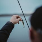 Angler holding baited hook beside rod at the transom